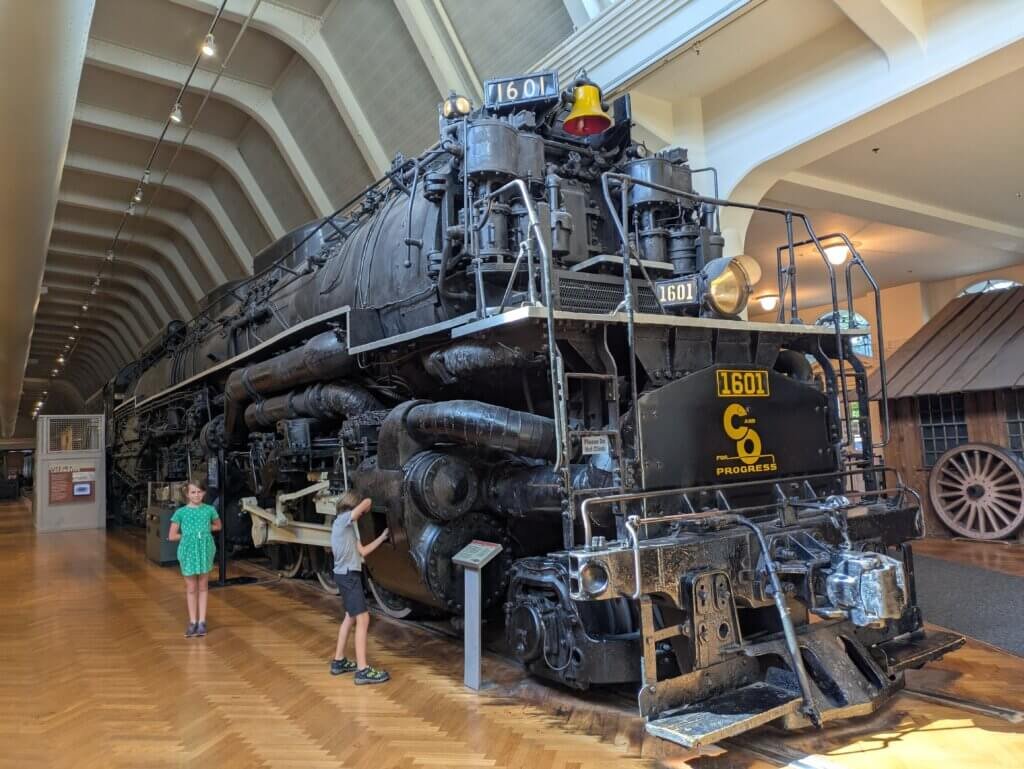 2 kids in front of large train engine
