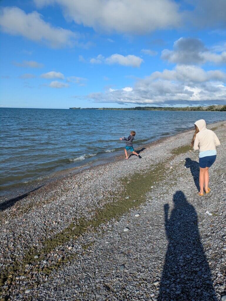 Kids walking shore and skipping stones on lake
