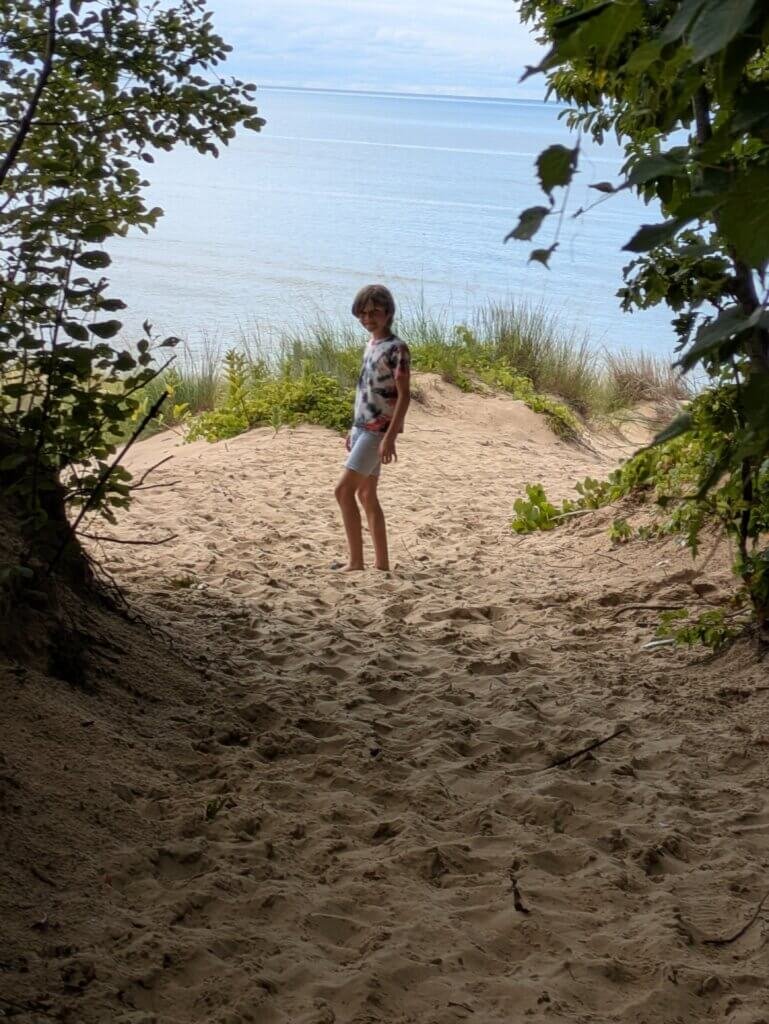 Boy standing in front of beach surrounded by trees