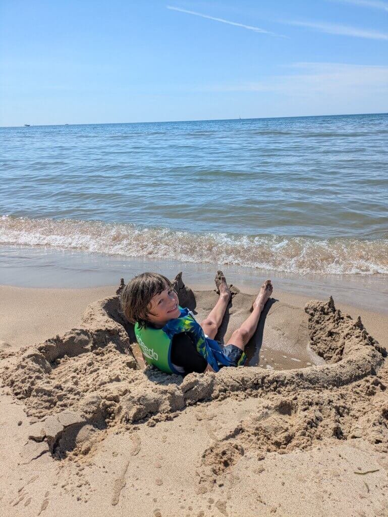 Kid sitting in sand near water at beach