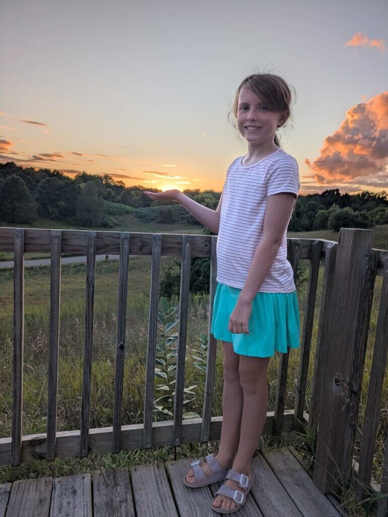 Girl holding sunset on deck