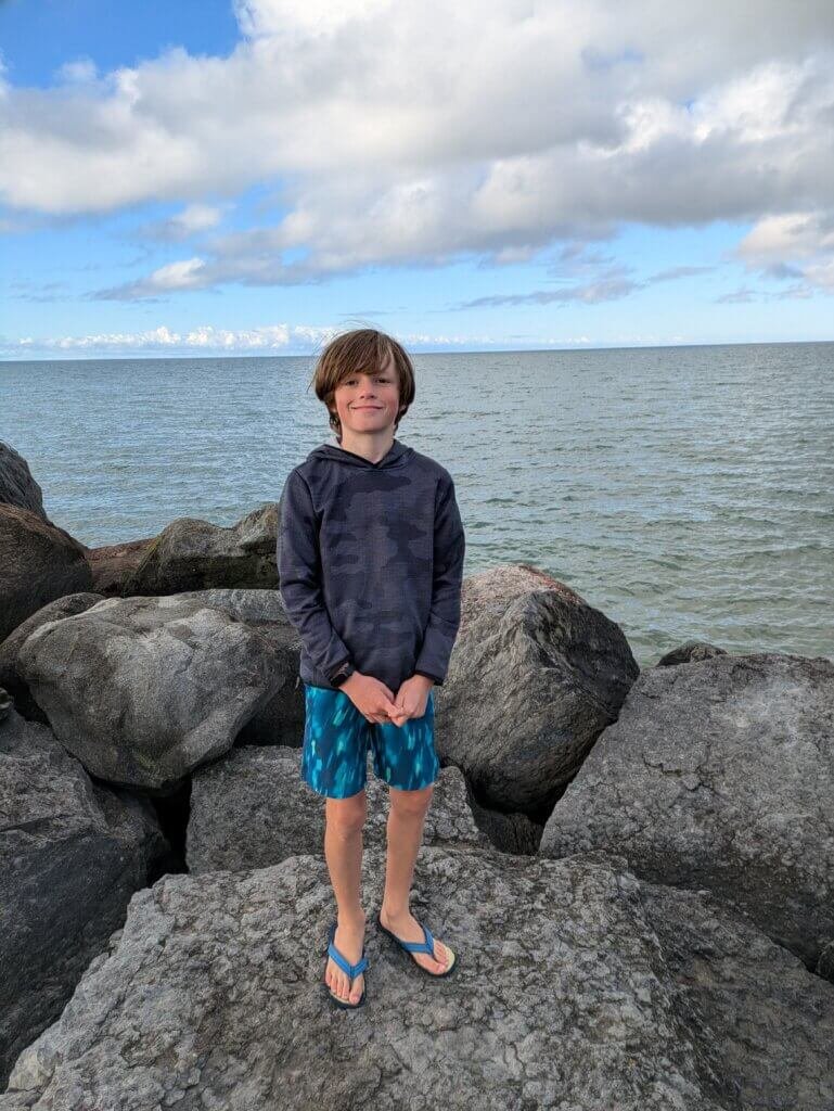 Boy on rocks in front of lake